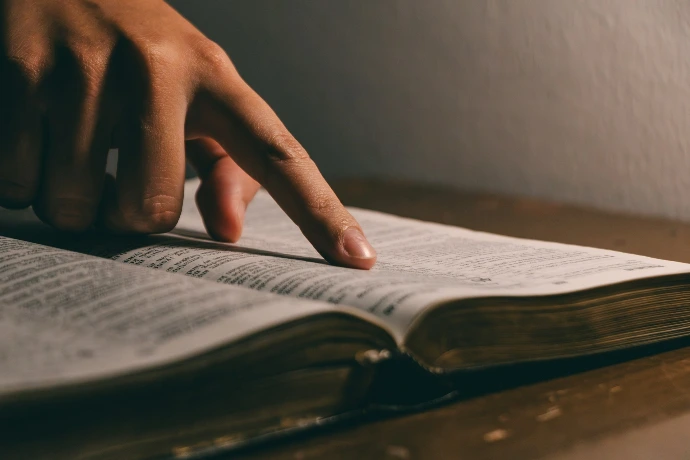 A finger points to words in an open book